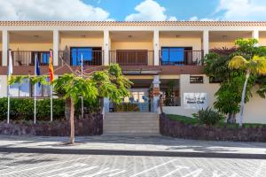 a building with palm trees in front of it at Royal Sunset Beach Club in Adeje