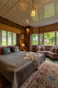 1 dormitorio con cama, sofá y ventanas en LohonoStays Villa Hill Retreat, en Pahalgām