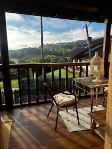 terraza de madera con mesa y silla en el balcón en APARTAMENTOS KERCUS, en Sevares
