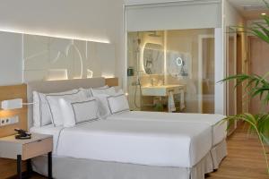1 Schlafzimmer mit einem großen weißen Bett und einem Badezimmer in der Unterkunft Melia Jardines del Teide - Adults Only in Adeje