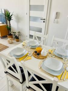 a white dining table with plates and glasses on it at BeeApartments Naściszowska 18 in Nowy Sącz