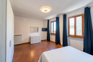 - une chambre avec un lit blanc et des rideaux bleus dans l'établissement BORGO SMOL, à Chianni