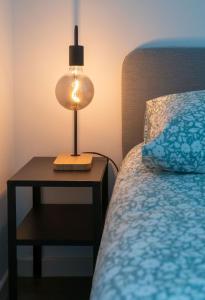 a lamp on a night stand next to a bed at Le Brit - Grand appartement design, 3 chambres, centre ville in Vichy
