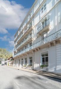 un edificio bianco con balconi su una strada di Le Brit - Grand appartement design, 3 chambres, centre ville a Vichy