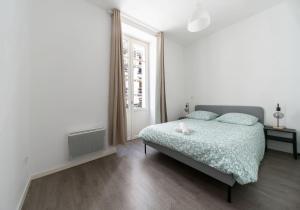a white bedroom with a bed and a window at Le Brit - Grand appartement design, 3 chambres, centre ville in Vichy
