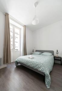 a bedroom with a bed with a green comforter and a window at Le Brit - Grand appartement design, 3 chambres, centre ville in Vichy