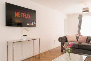 a living room with a couch and a tv on the wall at Prenton House, 3BR Close to Liverpool in Birkenhead