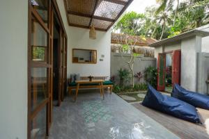 een patio met een tafel en blauwe kussens in een huis bij De Rekun Ubud in Ubud