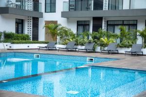 einen Pool mit Liegestühlen neben einem Gebäude in der Unterkunft Paradise 1 bedroom Apartment @Embassy Gardens in Cantonments