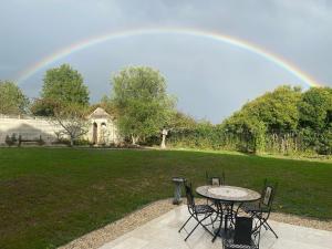 a rainbow over a patio with a table and chairs at The Little Robin in Chevanceaux