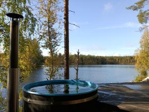 a hot tub sitting next to a lake at Upea kelohirsihuvila rannalla, myös poreamme! in Joensuu
