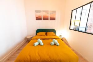 1 dormitorio con 1 cama amarilla y 2 almohadas en KASA ARTY - Tout équipé - Agréable et confortable en Saint-Étienne