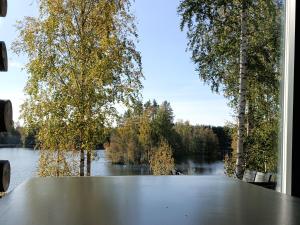 a table with a view of a river and trees at Upea kelohirsihuvila rannalla, myös poreamme! in Joensuu