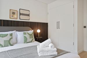 Schlafzimmer mit einem Bett mit grünen und weißen Kissen in der Unterkunft Bow Lane by Q Apartments in London