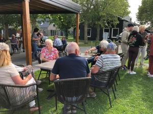 a group of people sitting at tables in a park at Chalet 561 op Recreatiepark De Wielen in Sint Maarten