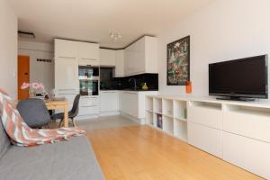 a kitchen with white cabinets and a flat screen tv at Sunny City Centre Apartment by Renters in Warsaw