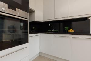 a kitchen with white cabinets and a sink at Sunny City Centre Apartment by Renters in Warsaw