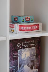 a shelf with books and a picture of a city at Sunny City Centre Apartment by Renters in Warsaw