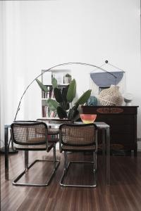 een glazen tafel met twee stoelen en een tafel met een plant bij ComeCasa Grazioso Loft in Crocetta in Milaan