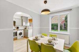 a kitchen and dining room with a white table and green chairs at Stunning Detached 3 Bed House - Parking & Garden in Bedford