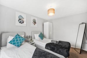 a bedroom with two beds with blue and white pillows at Stunning Detached 3 Bed House - Parking & Garden in Bedford