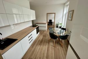a kitchen with white cabinets and a table and chairs at Sušilova 14 apartments III in Přerov