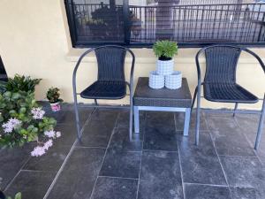 two chairs and a table on a porch with plants at Rose House in Deer Park