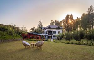 2 Stühle und ein Tisch im Hof mit einem Haus in der Unterkunft LohonoStays Red Cottage at Zaznar in Srinagar