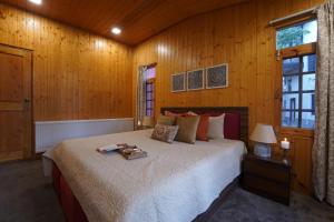 ein Schlafzimmer mit einem großen Bett in einem Holzzimmer in der Unterkunft LohonoStays Red Cottage at Zaznar in Srinagar