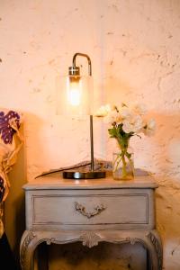 una mesa con una lámpara y un jarrón de flores. en Orange Door Bnb, en Currency Creek