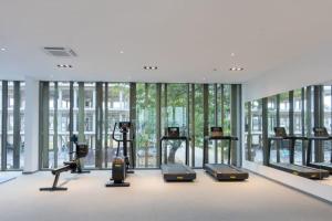 a gym with treadmills and ellipticals in a room with windows at Plush 1 Bedroom/Guest Washroom @The Lennox Airport in Accra