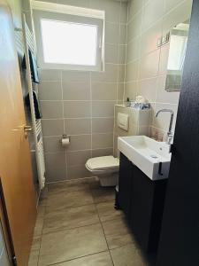 a bathroom with a toilet and a sink and a window at 2 P. Appartement am Kurpark in Bad Driburg