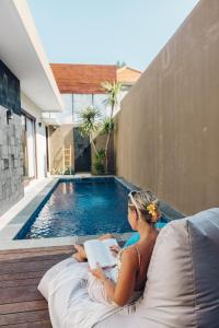 吉利特拉旺安Taj Maza Sunset Villas的坐在床上读书的女人在游泳池旁读书