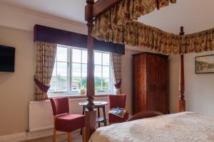 a bedroom with a canopy bed and chairs and a window at Blacksmiths Arms Inn in Scarborough