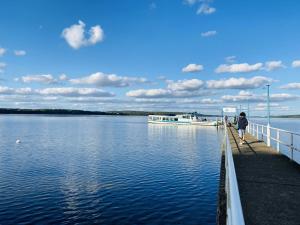 a person walking on a dock with a boat in the water at Seeglück 1 am Tollensesee in Groß Nemerow