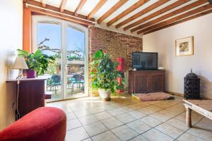 a living room with a tv and a brick wall at Escapade dans la campagne toulousaine in Beaumont-sur-Lèze