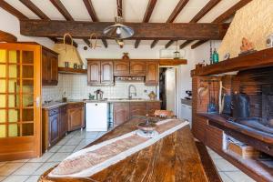a kitchen with wooden cabinets and a large wooden table at Escapade dans la campagne toulousaine in Beaumont-sur-Lèze