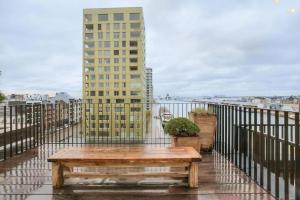 een houten bank op een balkon met een gebouw bij Unique Appartment view MAS! in Antwerpen