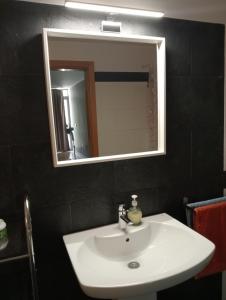 un bagno con un lavandino bianco e uno specchio di La Alameda Jardines del Prado -Amplio y con ascensor- a Talavera de la Reina Altre 30 foto