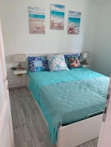 een slaapkamer met een bed met blauwe lakens en foto's aan de muur bij Villino Porto ottiolu in Porto Ottiolu