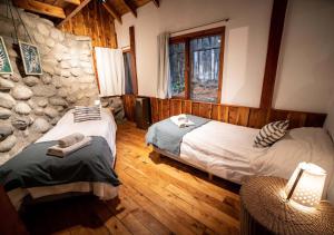 a bedroom with two beds and a stone wall at Ruma Andina by DOT Cabana in Villa La Angostura