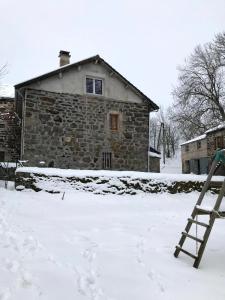 Una escalera en la nieve frente a una casa de piedra en Maison de famille plateau du Mezenc, en Les Vastres