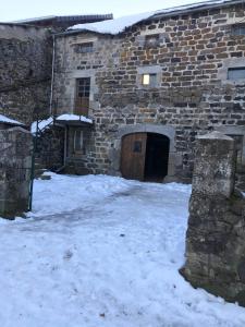 um edifício de pedra com uma porta na neve em Maison de famille plateau du Mezenc em Les Vastres
