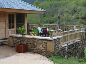 a deck with chairs and an umbrella on a cabin at CHALET BOIS PLEINE NATURE 6 PLACES in Sainte-Eulalie-dʼOlt