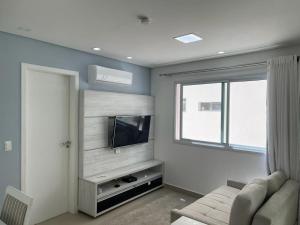 un salon avec un canapé et une télévision à écran plat dans l'établissement Lindo Apto Guarujá 50m da Praia das Pitangueiras, à Guarujá