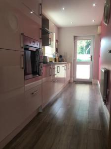 a kitchen with white cabinets and a wooden floor at The Riverside Apartment on Cheddar Bridge Apartments in Cheddar