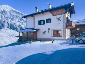 a house in the snow with a car parked in front at Hotel Aquila in Livigno