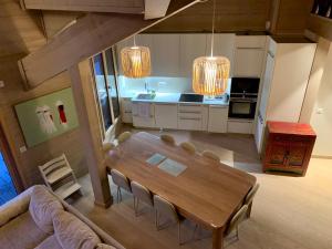 cocina y comedor con mesa de madera y sillas en Le chalet sous-toiture Nánshān : spacieux, lumineux et idéalement situé à Auron, en Auron