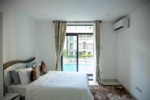 a bedroom with a bed and a large window at Pool View Apartment @Embassy Gardens in Cantonments +71 photos