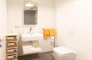 a white bathroom with a sink and a toilet at Portopiccolo Avolare Apartments in Borgo, beach included in Sistiana +22 photos